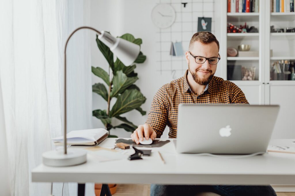 PF_team member Adult male working remotely in a stylish home office with a laptop, displaying a modern workspace.