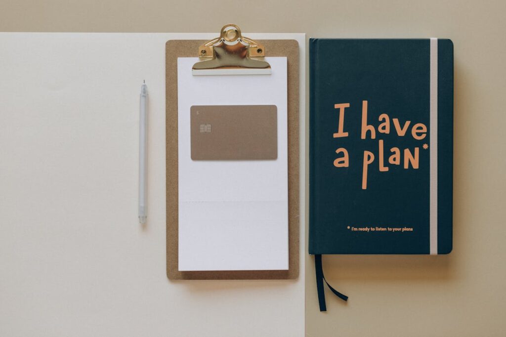 PF_we are ready to listen A minimalist office setup featuring a planner, clipboard, card, and pen, perfect for planning and organization.